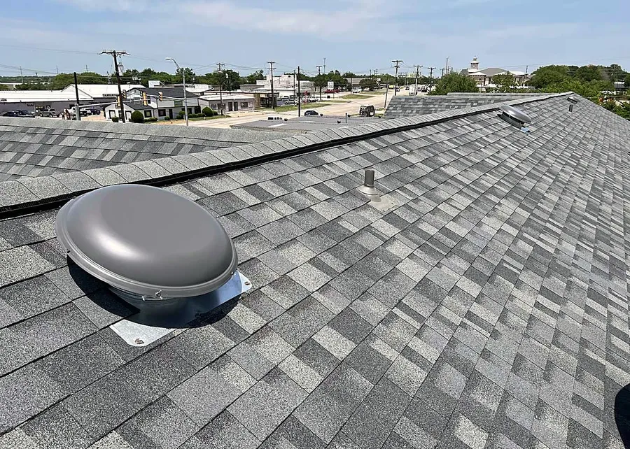 A close view of new gray shingles around a roof vent