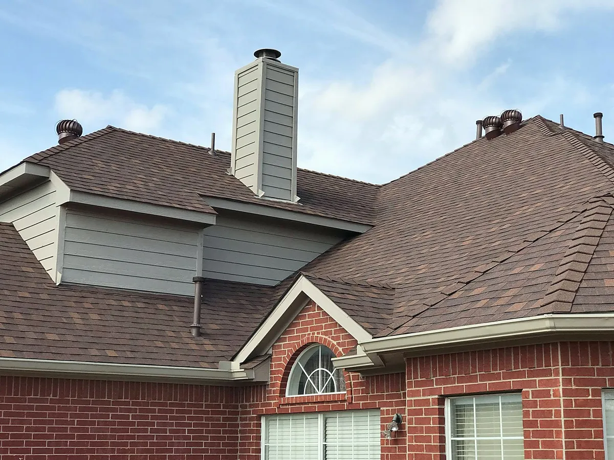 A red brick home with a new brown shingle roof