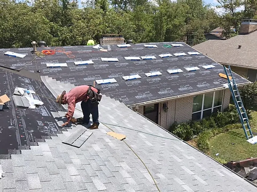 A roofer laying new shingles over fresh underlayment