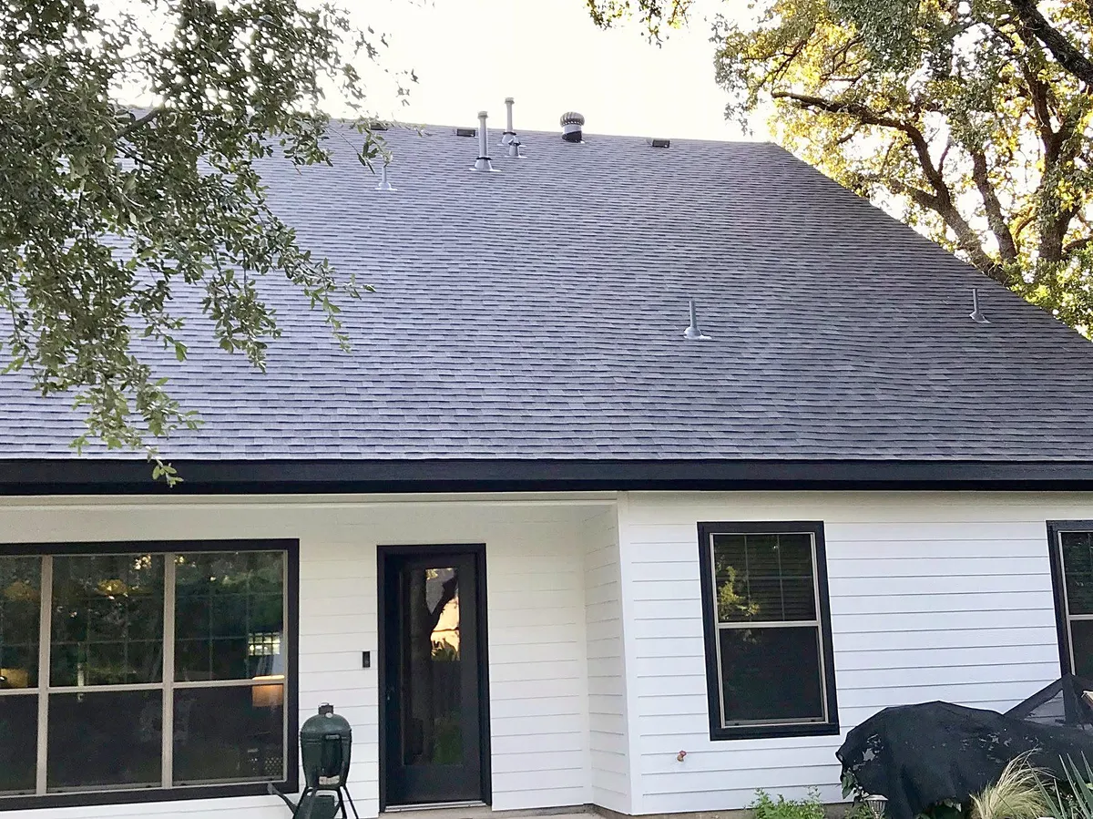 A white-sided home with a new dark shingle roof